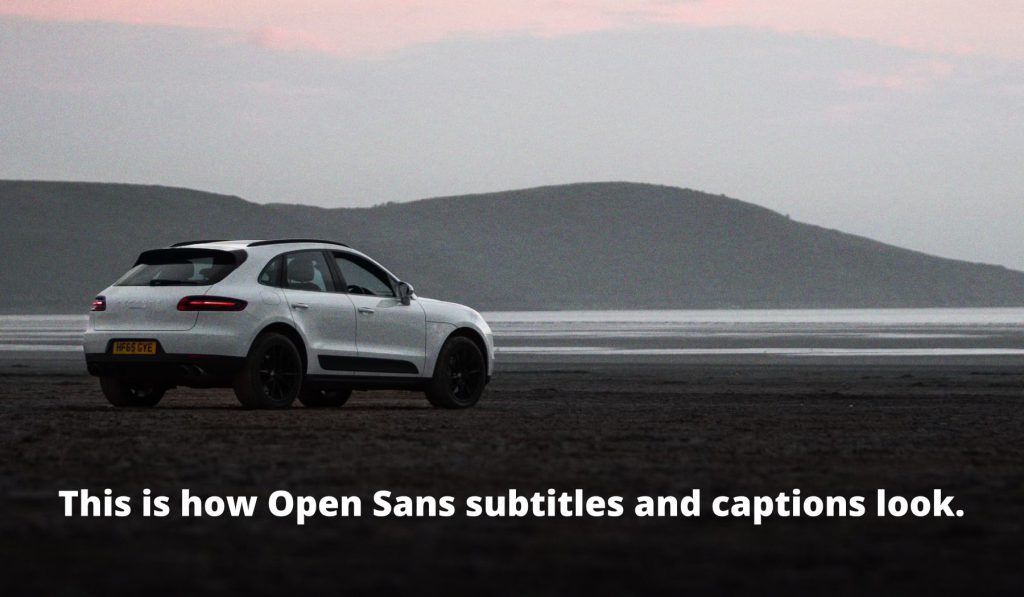 A white Porsche Macan parked on a beach at dusk. Text reads: "This is how Open Sans subtitles and captions look."